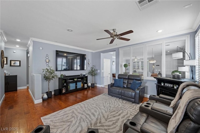 living area featuring baseboards, wood finished floors, visible vents, and crown molding