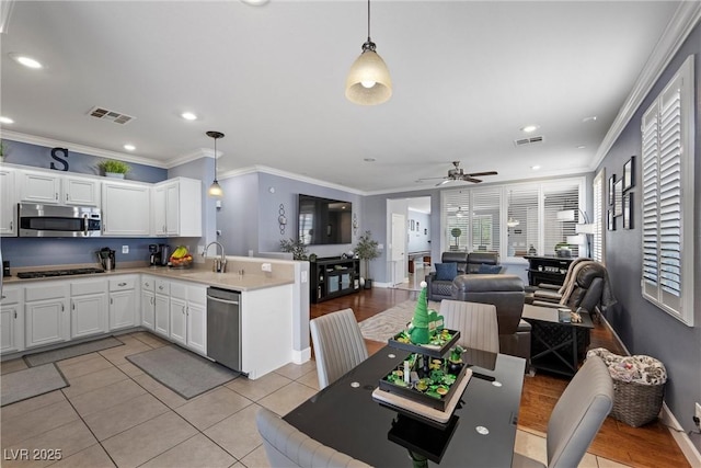 kitchen with visible vents, open floor plan, a peninsula, stainless steel appliances, and light tile patterned flooring