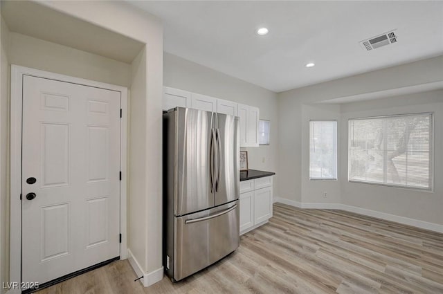 kitchen with visible vents, baseboards, white cabinets, light wood-type flooring, and freestanding refrigerator