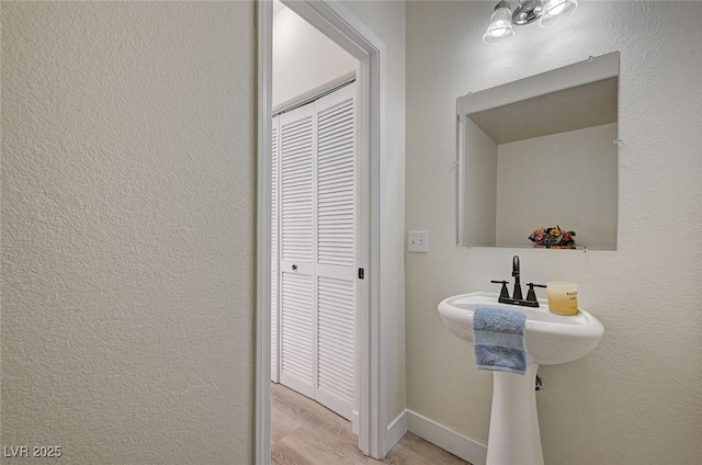 bathroom featuring a textured wall, wood finished floors, and baseboards