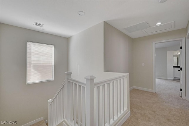 hallway with visible vents, baseboards, an upstairs landing, carpet, and attic access