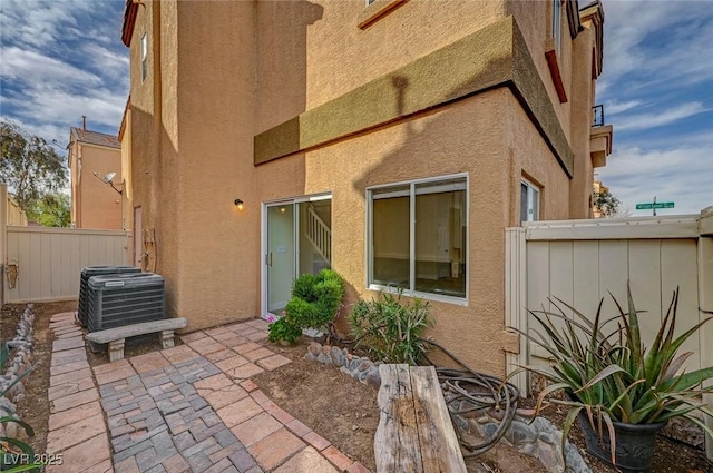 back of property with cooling unit, stucco siding, a patio, and fence