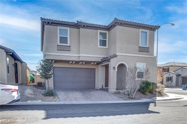 view of front of house with cooling unit, a garage, a tile roof, decorative driveway, and stucco siding