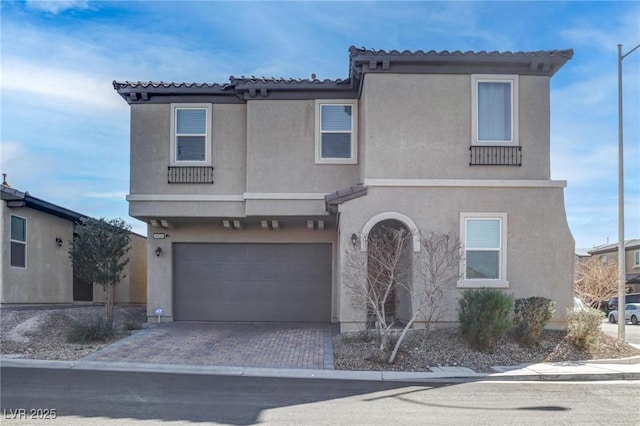 view of front facade featuring decorative driveway, an attached garage, and stucco siding