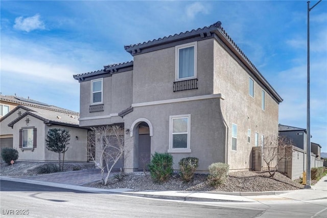 view of front facade featuring decorative driveway, a tile roof, an attached garage, and stucco siding