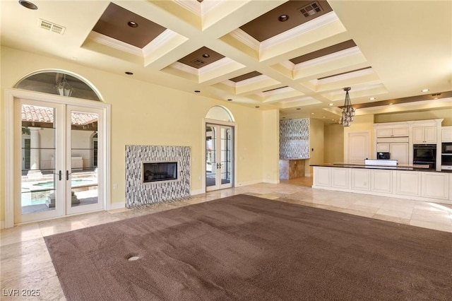 unfurnished living room featuring coffered ceiling, french doors, visible vents, and beamed ceiling