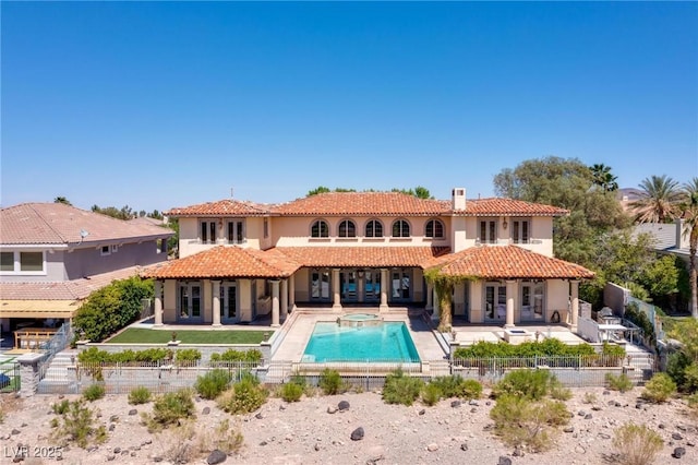 back of property with a tile roof, a chimney, a fenced backyard, a patio area, and stucco siding