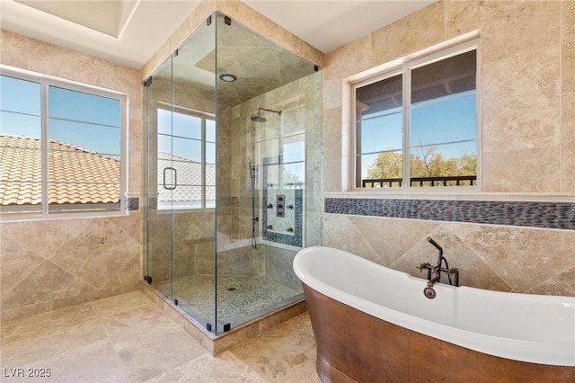 full bath with a freestanding bath, a stall shower, tile walls, and tile patterned floors