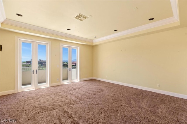 carpeted spare room with ornamental molding, a tray ceiling, french doors, and visible vents