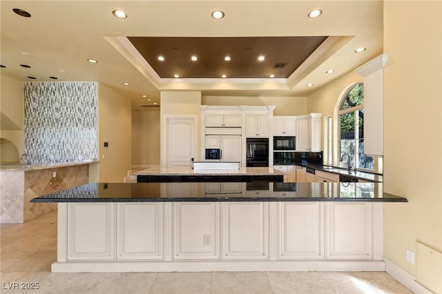 kitchen featuring built in appliances, a tray ceiling, a spacious island, and recessed lighting