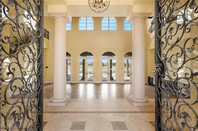 foyer featuring a chandelier, light tile patterned floors, and decorative columns