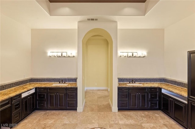 interior space featuring a tray ceiling, visible vents, arched walkways, and a sink