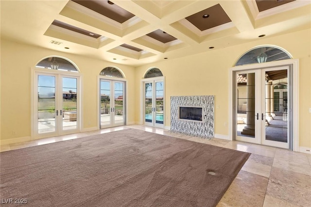 unfurnished living room featuring beam ceiling, french doors, a high ceiling, a premium fireplace, and baseboards