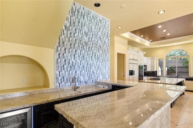 kitchen with a spacious island, wine cooler, recessed lighting, and light stone countertops