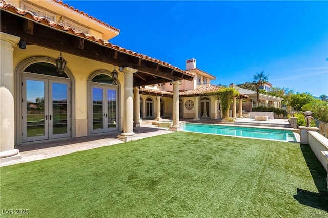 back of property featuring a lawn, a chimney, french doors, a patio area, and stucco siding