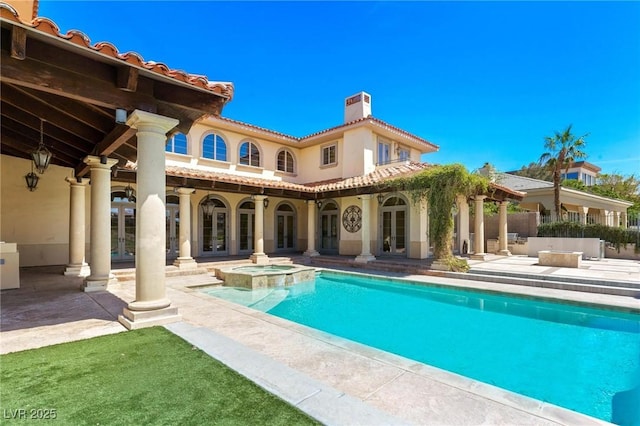 back of property featuring a chimney, a tiled roof, french doors, a patio area, and stucco siding