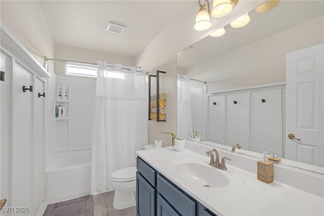 bathroom featuring visible vents, toilet, vanity, and shower / tub combo