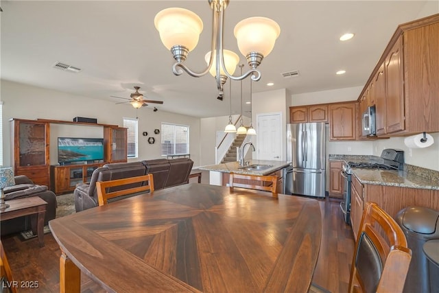 dining room with dark wood-type flooring, ceiling fan with notable chandelier, and visible vents