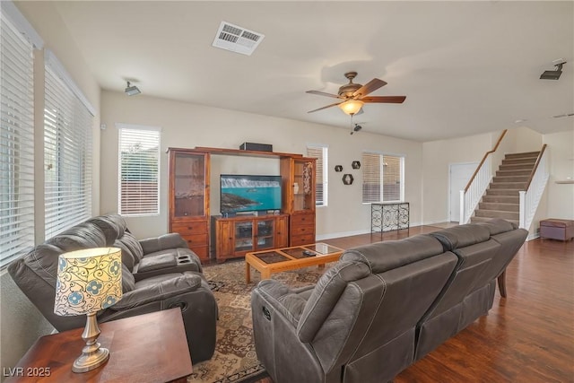 living area with visible vents, baseboards, stairs, wood finished floors, and a ceiling fan