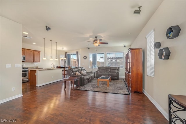 living area with dark wood-type flooring, a ceiling fan, visible vents, and baseboards