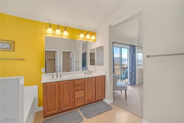 bathroom with a sink, baseboards, double vanity, and a washtub