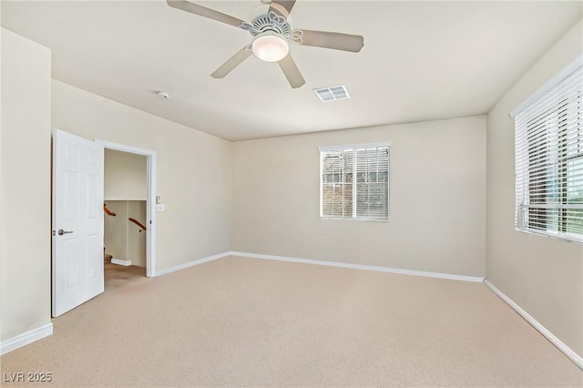 unfurnished bedroom featuring baseboards, visible vents, light colored carpet, a ceiling fan, and a walk in closet