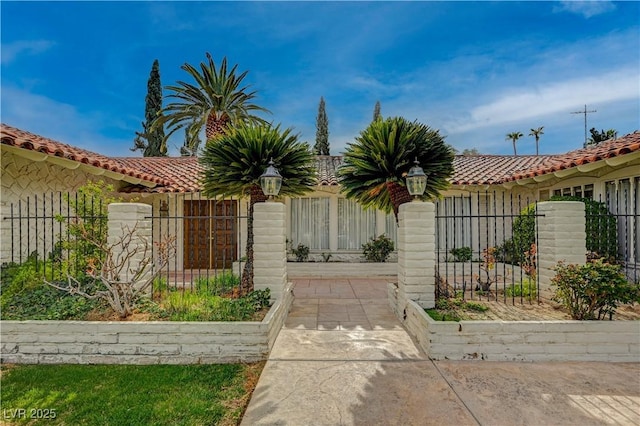 view of front of property featuring a gate, fence, and a tiled roof