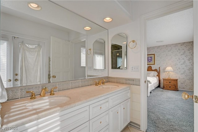 ensuite bathroom featuring wallpapered walls, a wealth of natural light, and a sink