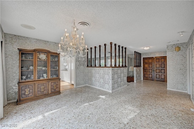 interior space with wallpapered walls, visible vents, a textured ceiling, and speckled floor