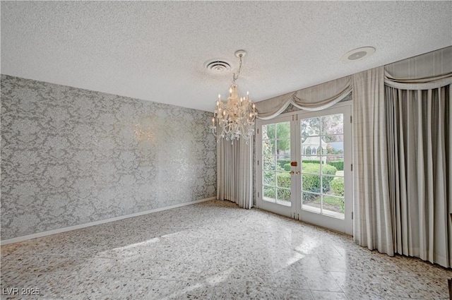 spare room featuring visible vents, a textured ceiling, a chandelier, baseboards, and wallpapered walls