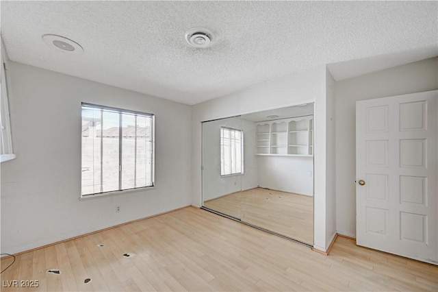 unfurnished room featuring visible vents, a textured ceiling, and wood finished floors