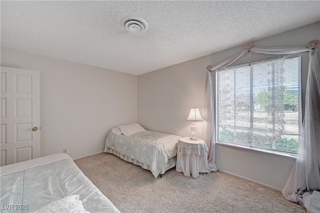 bedroom featuring a textured ceiling, multiple windows, visible vents, and carpet flooring