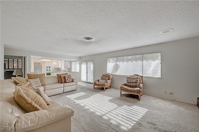 living area featuring carpet floors, visible vents, and a textured ceiling