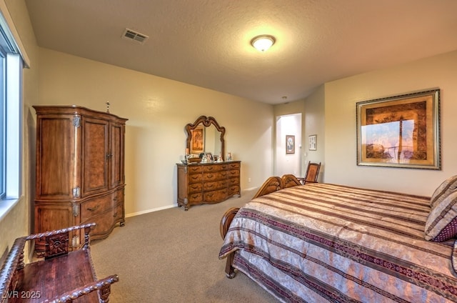 bedroom with baseboards, a textured ceiling, visible vents, and carpet flooring