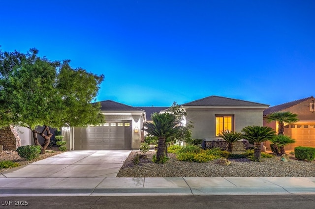 view of front of home with a garage, a tile roof, driveway, and stucco siding