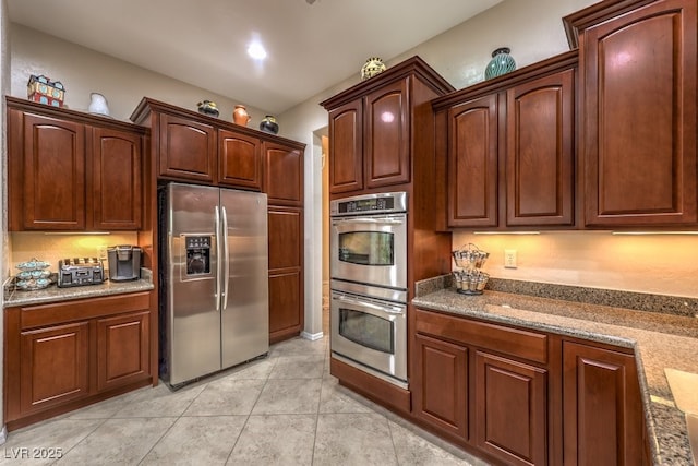 kitchen with stainless steel appliances, stone countertops, and light tile patterned floors