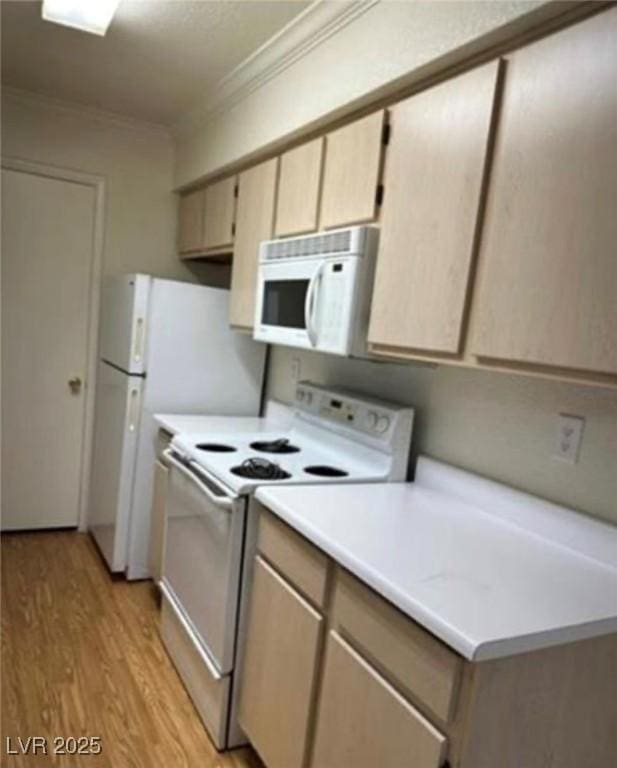 kitchen with light wood finished floors, light countertops, white appliances, and ornamental molding