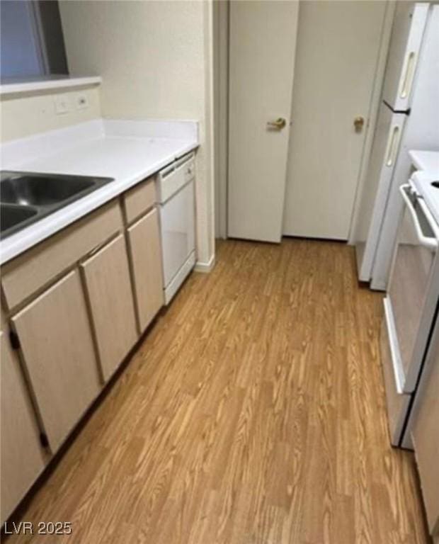 kitchen with light countertops, light wood-style floors, a sink, range, and dishwasher