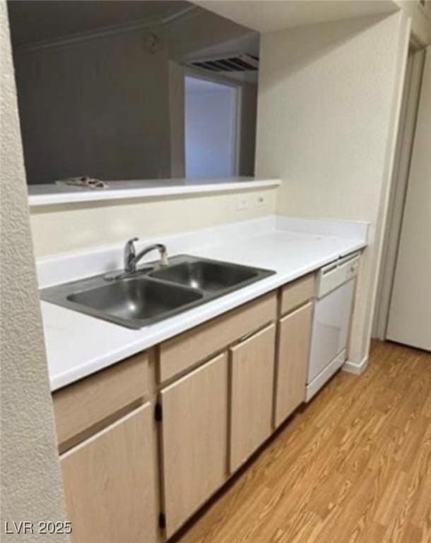 kitchen with light countertops, dishwasher, light wood-style flooring, and a sink