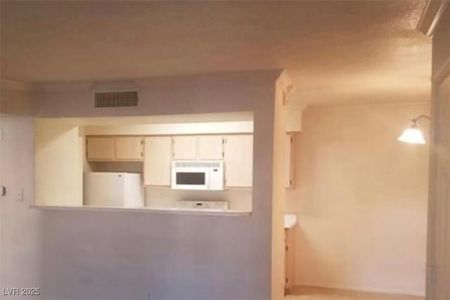 kitchen featuring refrigerator, visible vents, and white microwave