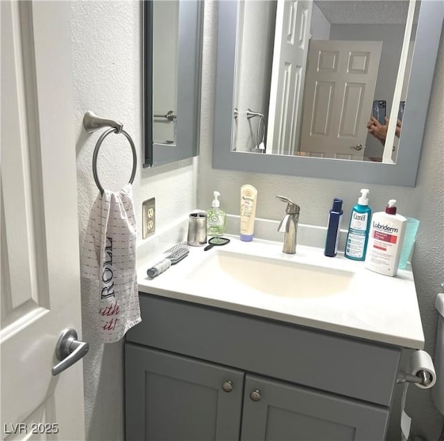 bathroom featuring a textured wall and vanity