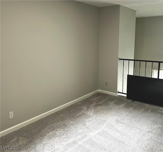 unfurnished room with baseboards, dark colored carpet, and a textured ceiling