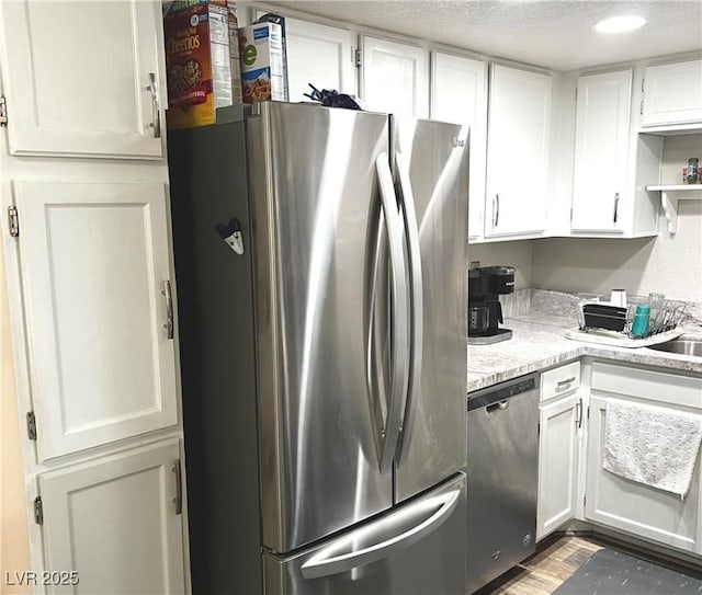 kitchen with a textured ceiling, stainless steel appliances, open shelves, and white cabinets