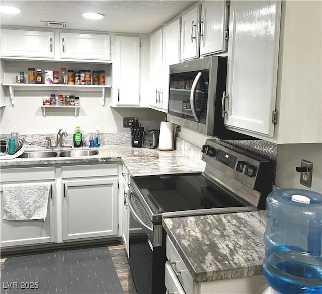 kitchen with white cabinetry, appliances with stainless steel finishes, open shelves, and a sink