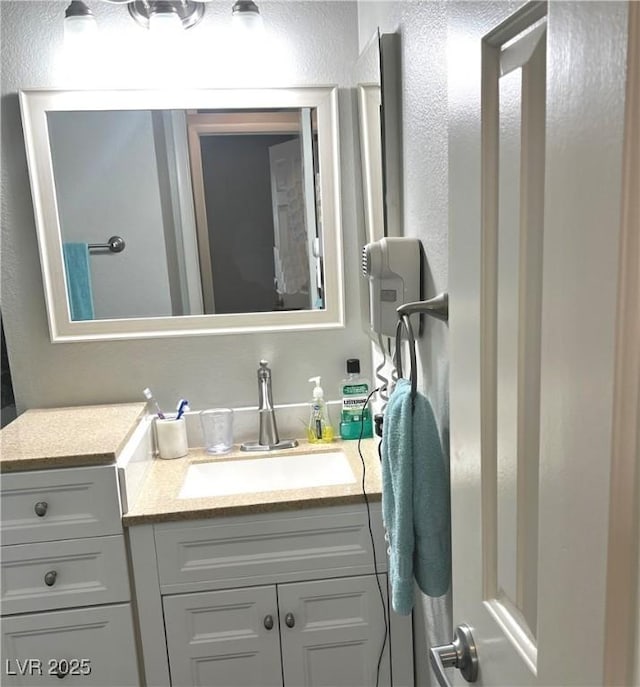 bathroom featuring a textured wall and vanity