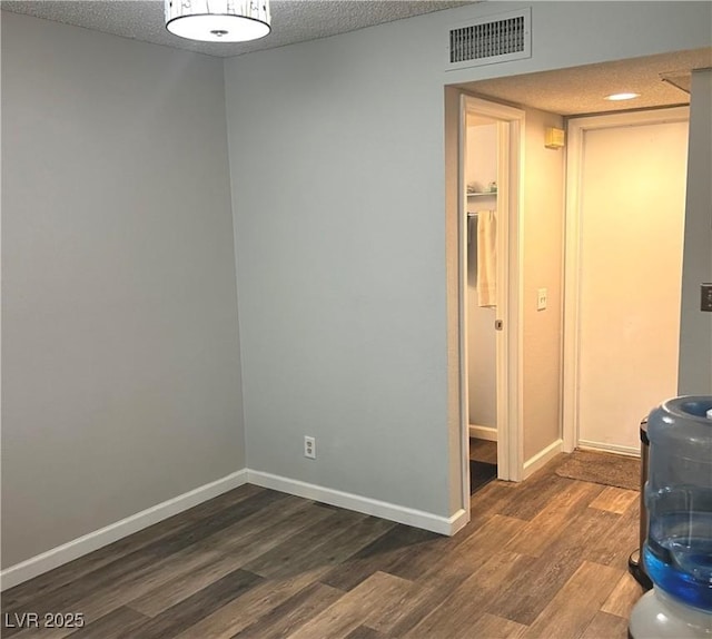 interior space with visible vents, dark wood finished floors, a textured ceiling, and baseboards