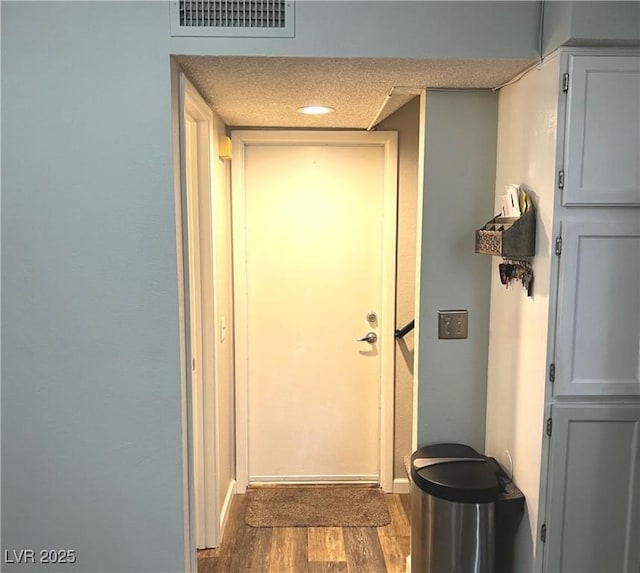 doorway featuring a textured ceiling, wood finished floors, and visible vents