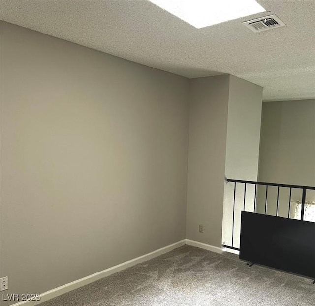 unfurnished room featuring a textured ceiling, dark carpet, visible vents, and baseboards