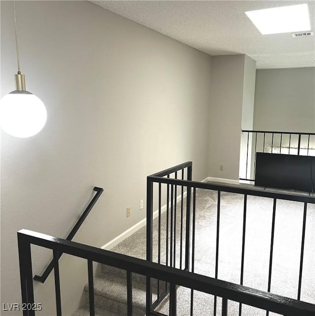 stairs with carpet flooring, visible vents, a textured ceiling, and baseboards