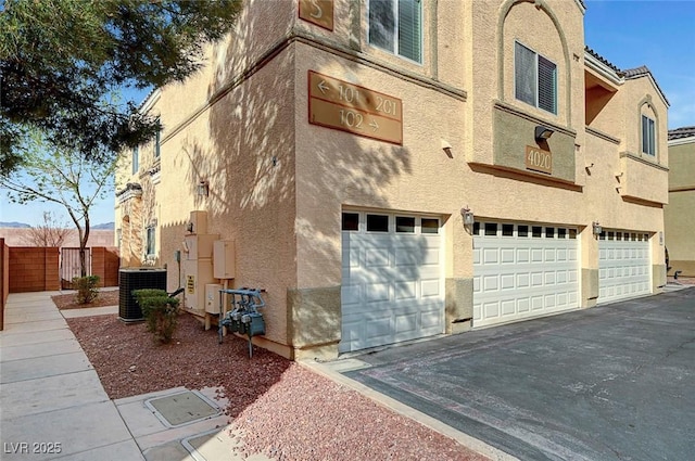 view of home's exterior with an attached garage, cooling unit, and stucco siding